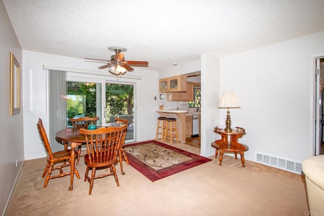 dining room with carpet flooring, a textured ceiling, baseboards, visible vents, and a ceiling fan