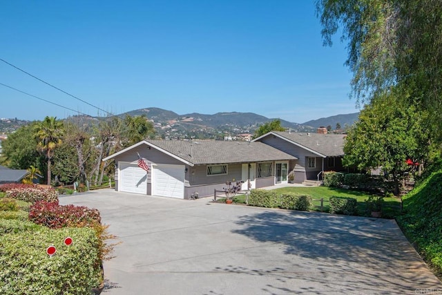 ranch-style home with a front lawn, driveway, a mountain view, and a garage