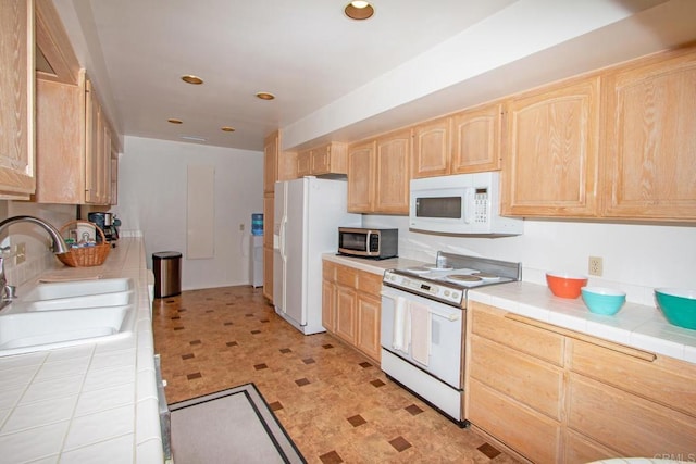 kitchen with a sink, white appliances, light floors, light brown cabinets, and tile countertops