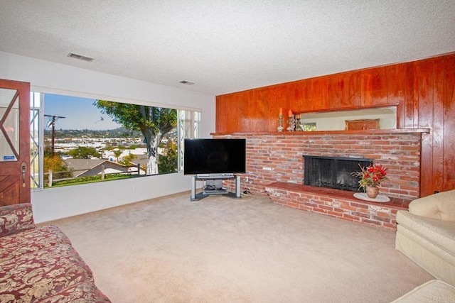 carpeted living area with a fireplace, a textured ceiling, visible vents, and wood walls