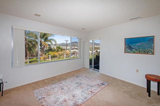 unfurnished room with baseboards, visible vents, carpet, and a textured ceiling