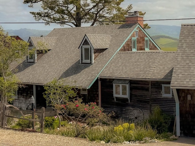 cape cod home featuring a chimney, a mountain view, and roof with shingles
