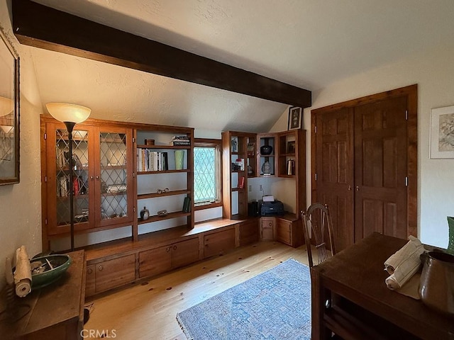 interior space with light wood-type flooring and vaulted ceiling with beams