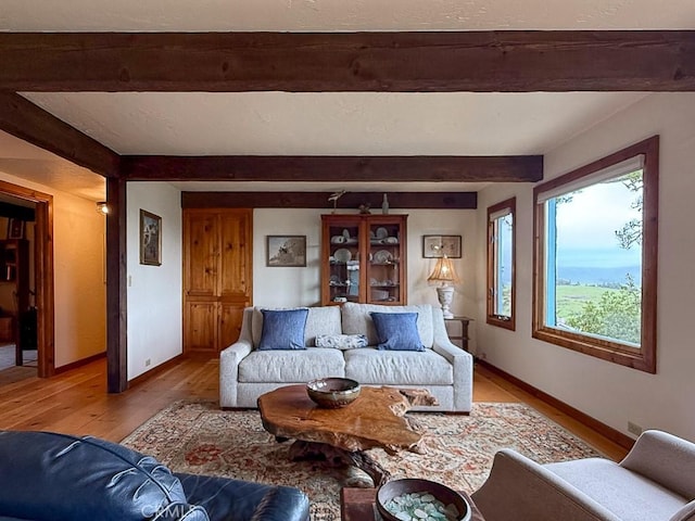living area with light wood-type flooring, baseboards, and beam ceiling