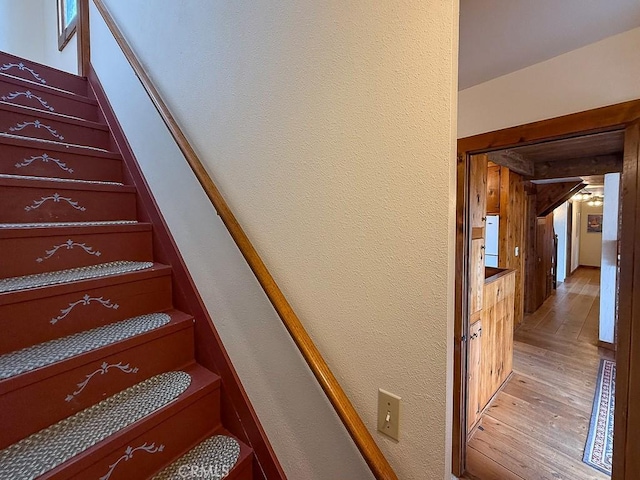 staircase with wood-type flooring and a textured wall