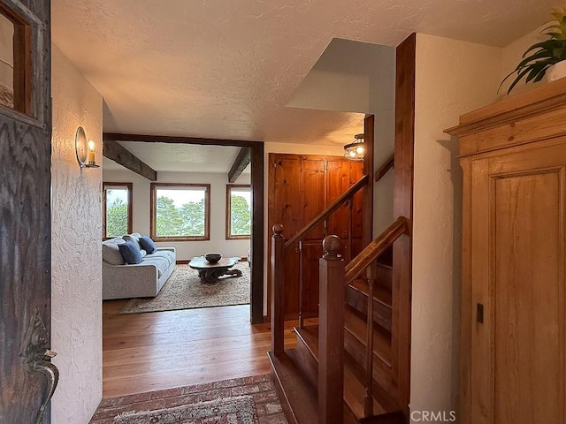 interior space featuring wood-type flooring, stairway, a textured ceiling, and a textured wall