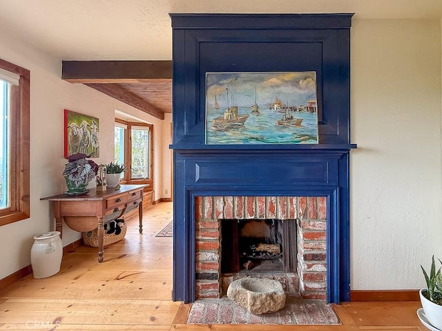 room details featuring baseboards, wood finished floors, beam ceiling, and a brick fireplace