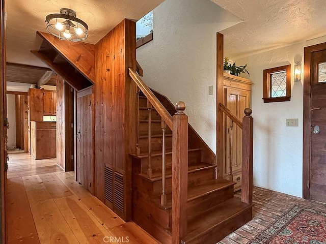 stairs with a textured wall and a textured ceiling