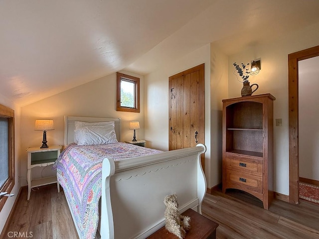 bedroom featuring lofted ceiling, wood finished floors, and baseboards