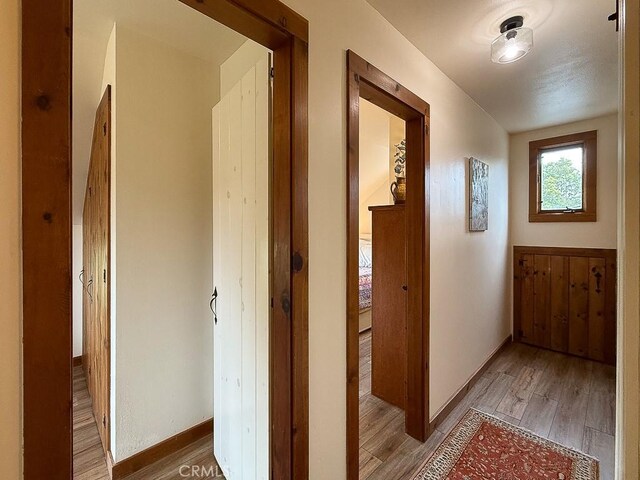 corridor featuring light wood finished floors and baseboards