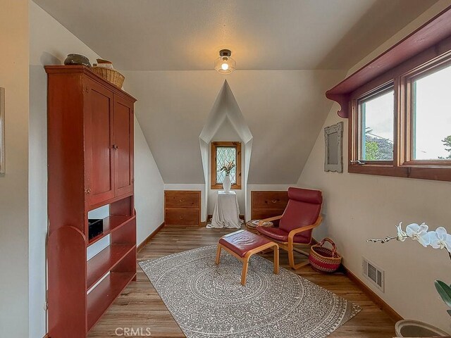 living area featuring vaulted ceiling, baseboards, light wood-style floors, and visible vents
