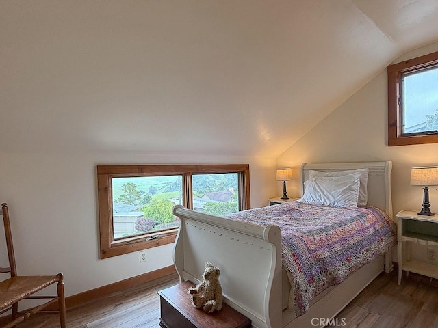 bedroom with lofted ceiling, baseboards, and wood finished floors