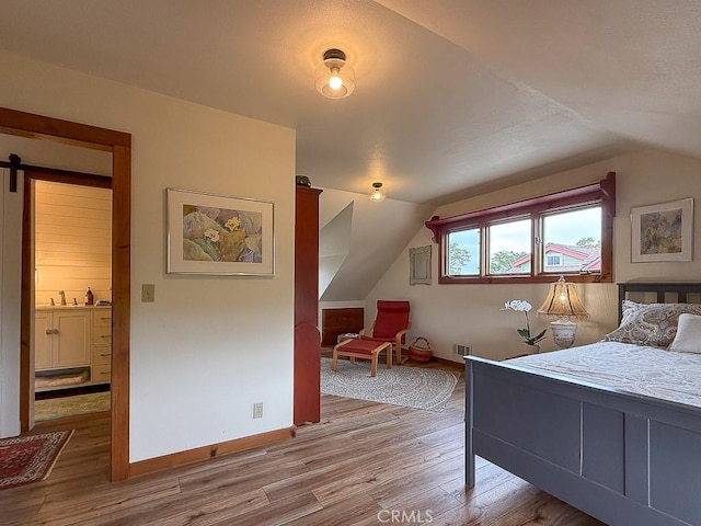bedroom featuring vaulted ceiling, wood finished floors, and baseboards