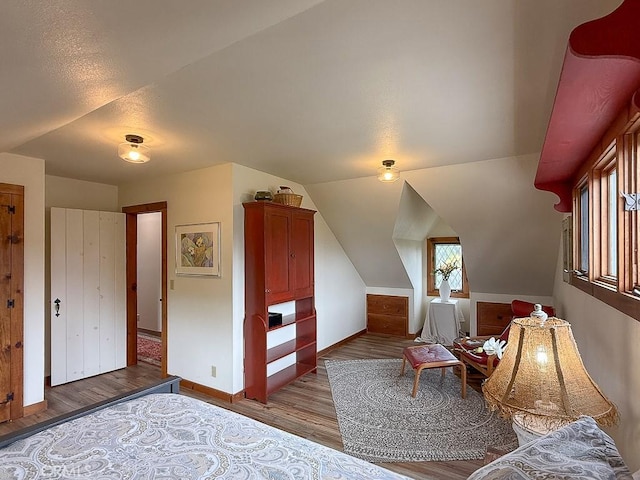 bedroom with vaulted ceiling, baseboards, and wood finished floors