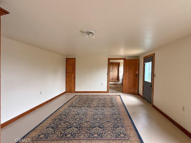 empty room featuring a textured ceiling, baseboards, and visible vents