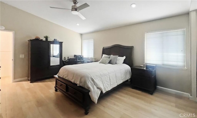 bedroom featuring light wood finished floors, multiple windows, baseboards, and lofted ceiling
