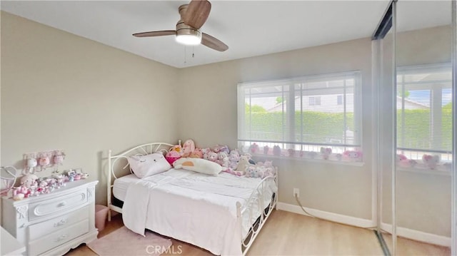 bedroom with ceiling fan, light wood-style flooring, and baseboards