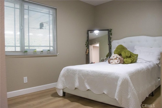 bedroom featuring multiple windows, wood finished floors, and baseboards