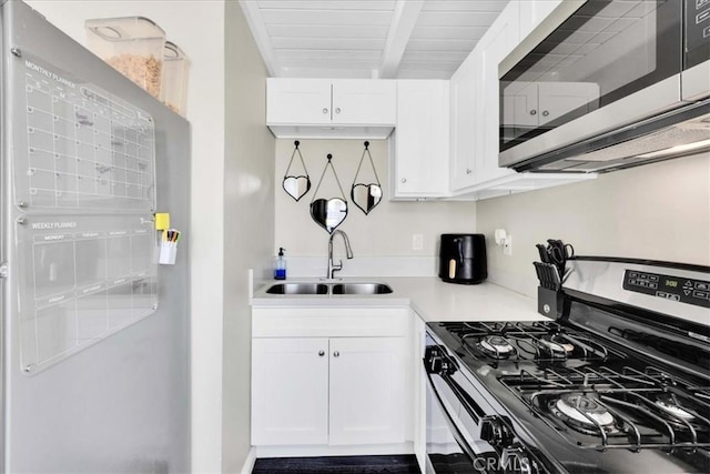 6558 Juniper Ave Unit 29, Palms, CA 92277 - kitchen featuring a sink, light countertops, beamed ceiling, white cabinetry, and appliances with stainless steel finishes