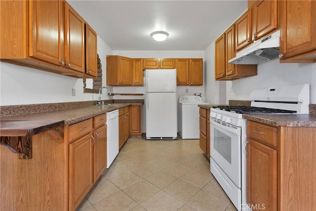 305 Beverly Ave, Barstow, CA 92311 - kitchen featuring white appliances, under cabinet range hood, washer / clothes dryer, dark countertops, and brown cabinets