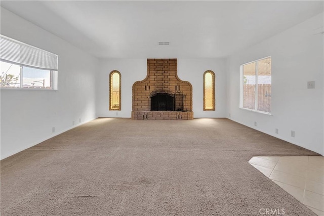 305 Beverly Ave, Barstow, CA 92311 - unfurnished living room featuring carpet flooring, plenty of natural light, a fireplace, and tile patterned floors