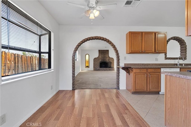 305 Beverly Ave, Barstow, CA 92311 - kitchen featuring a ceiling fan, dishwashing machine, arched walkways, light wood-style flooring, and brown cabinetry