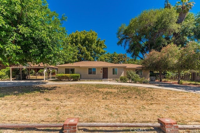 single story home featuring a front lawn, a carport, concrete driveway, fence, and stucco siding