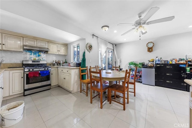 kitchen featuring cream cabinets, under cabinet range hood, ceiling fan, and stainless steel gas range
