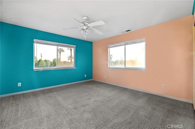 carpeted spare room with baseboards, visible vents, and ceiling fan