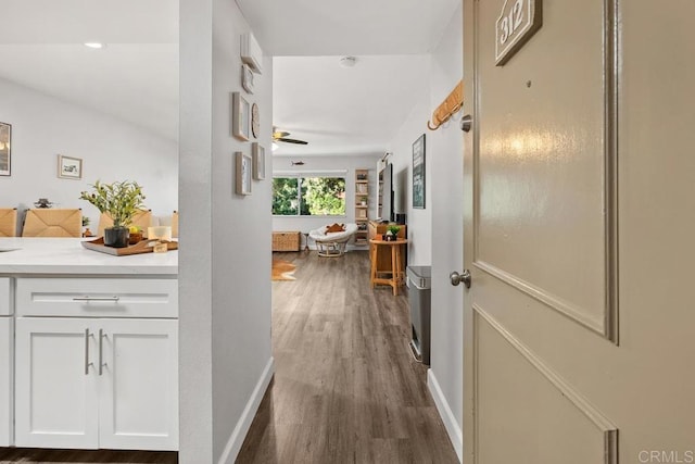 corridor featuring dark wood-style flooring and baseboards