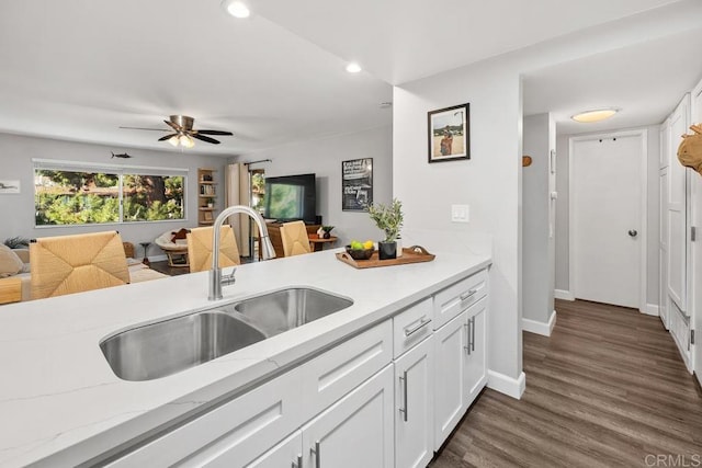 kitchen featuring white cabinetry, open floor plan, and a sink