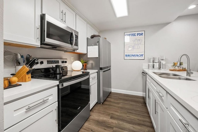 kitchen with baseboards, stainless steel appliances, white cabinetry, and a sink