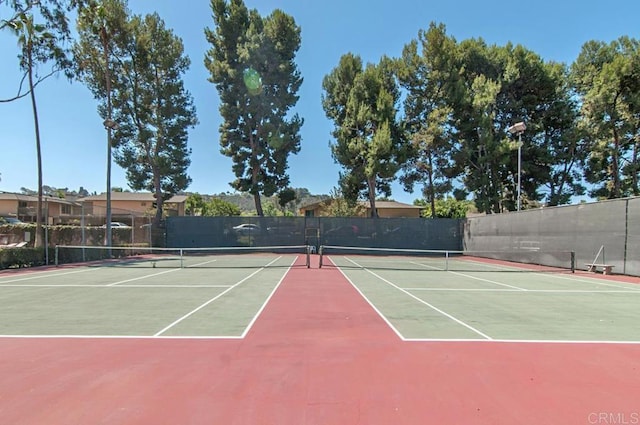 view of tennis court with community basketball court and fence