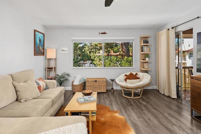 living area with baseboards, ceiling fan, and wood finished floors