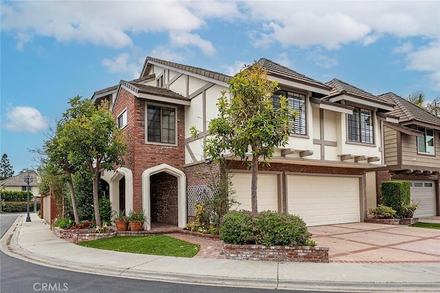 view of front facade with stucco siding, driveway, brick siding, and a garage