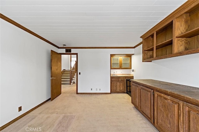 interior space featuring open shelves, light carpet, baseboards, and crown molding