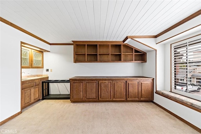 kitchen featuring light carpet, baseboards, and crown molding