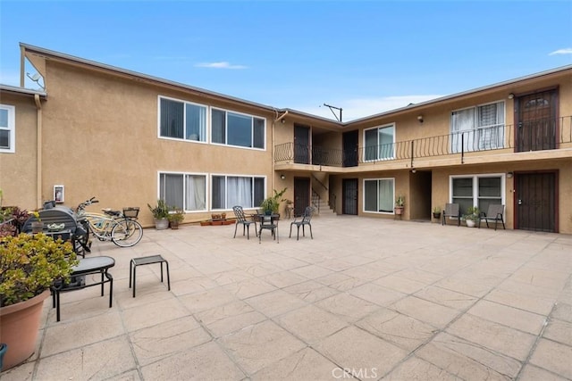 back of property with stairs, a patio, and stucco siding