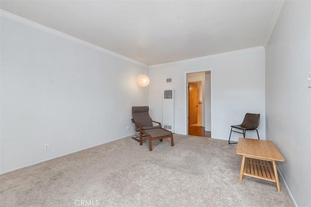 sitting room with carpet floors, visible vents, and ornamental molding