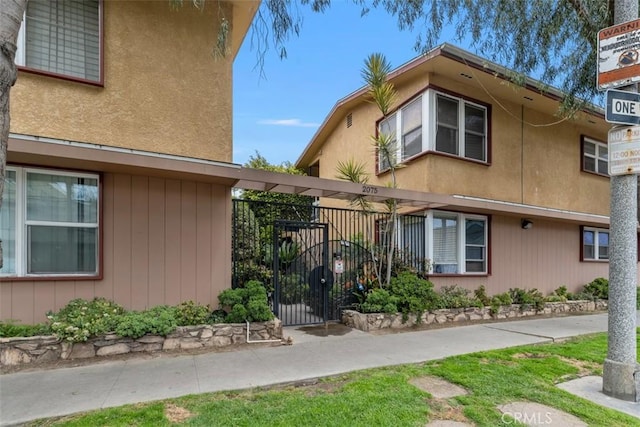 view of front of property with fence, a gate, and stucco siding