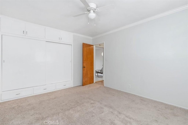 carpeted spare room featuring ceiling fan and ornamental molding