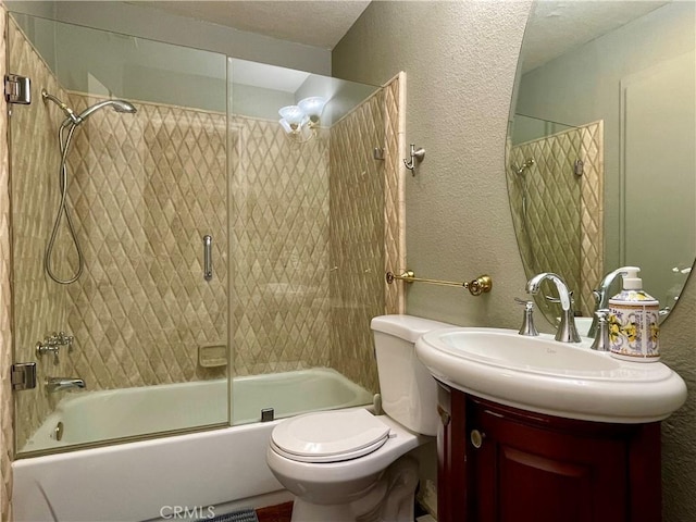 full bathroom with a textured wall, combined bath / shower with glass door, toilet, and vanity