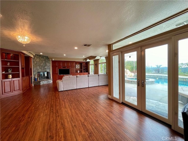 21062 Quail Run Dr, Diamond Bar, CA 91789 - unfurnished living room featuring a textured ceiling, dark wood-style flooring, french doors, a stone fireplace, and built in shelves