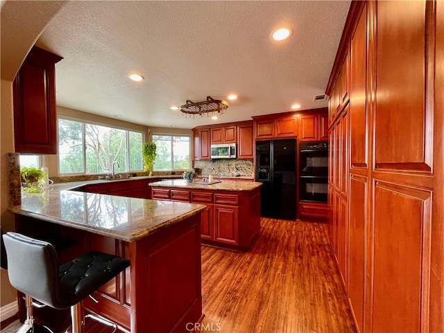 kitchen with a peninsula, dark wood-style floors, a textured ceiling, recessed lighting, and black appliances