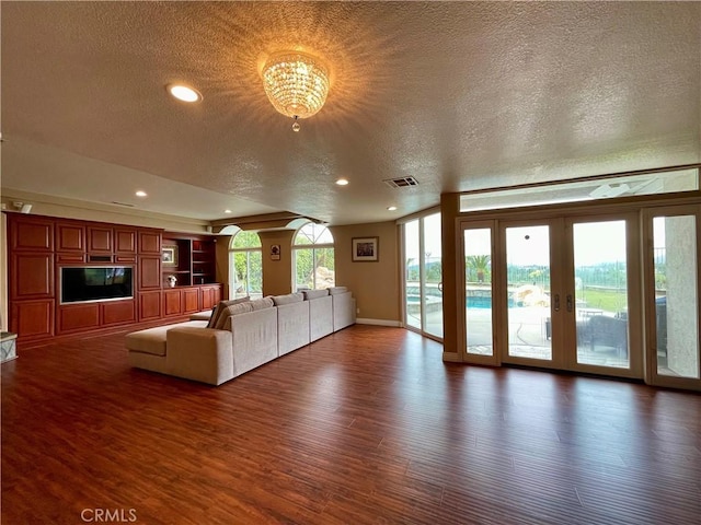 unfurnished living room featuring french doors, a textured ceiling, visible vents, recessed lighting, and wood finished floors