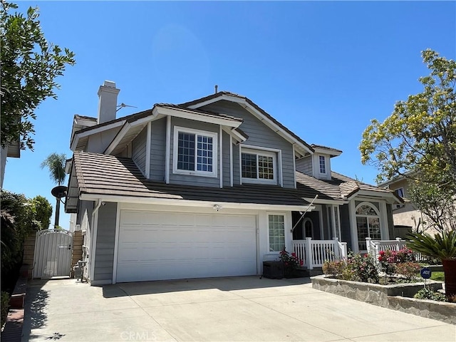 traditional-style home featuring a gate, driveway, a porch, a chimney, and a garage