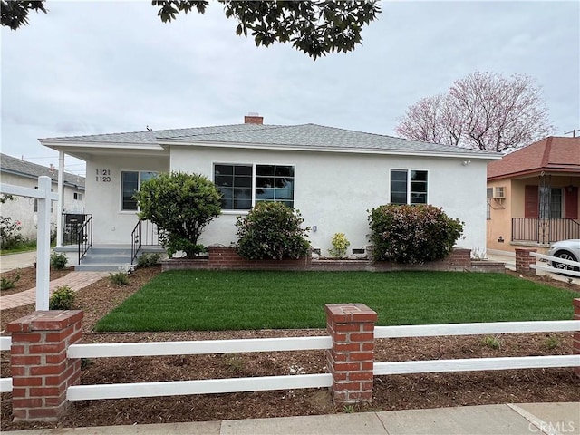bungalow-style home with a shingled roof, fence, stucco siding, and a front yard