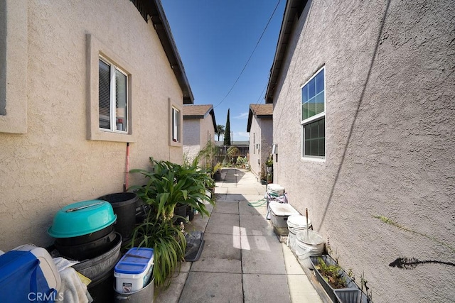 view of property exterior with stucco siding, fence, and a patio area