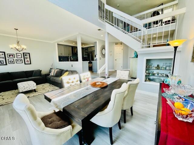 dining room with a towering ceiling, wood finished floors, a chandelier, and baseboards