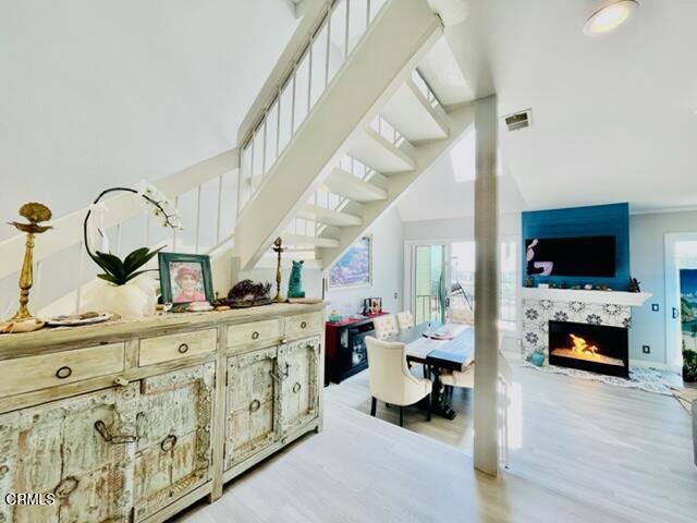 interior space featuring stairway, a towering ceiling, visible vents, and light wood-style flooring